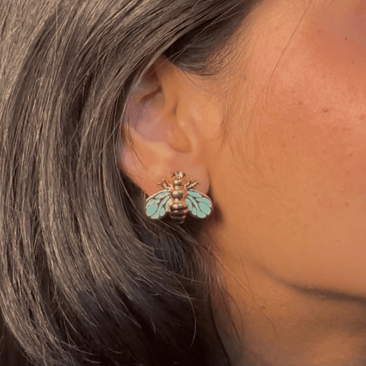 Bee stud earrings on gold-tone posts with blue enamel wings and striped bodies
