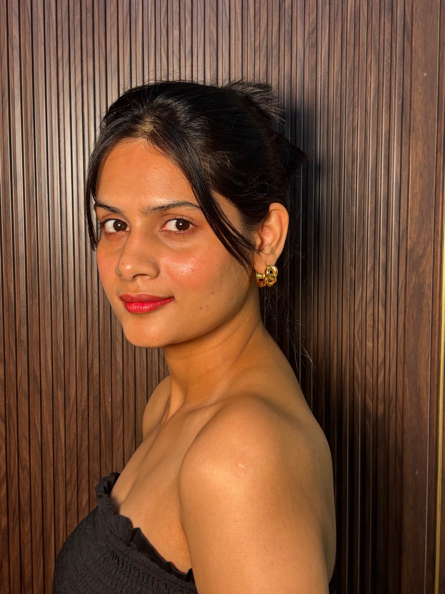 Gold chunky hoop earrings worn by a woman with hair pulled back