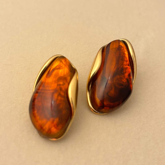 Oval teardrop resin earrings with amber-orange and dark brown swirls, gold-tone bezel