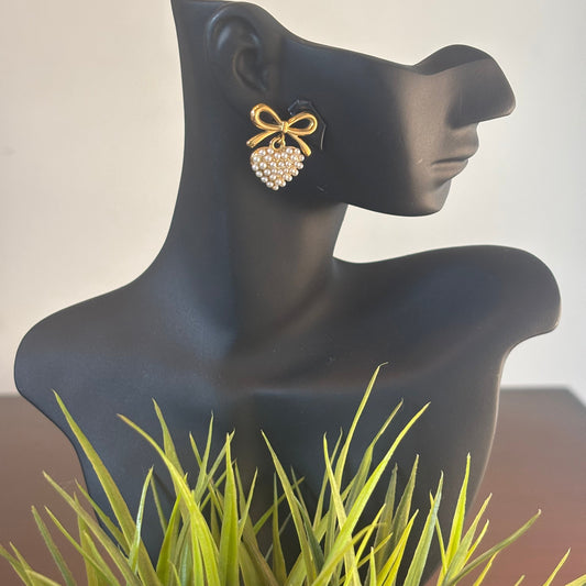 Pearl heart earrings with gold-tone bow detail on ear