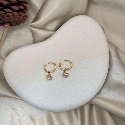 Gold huggie hoop earrings with two round evil eye charms, blue center details