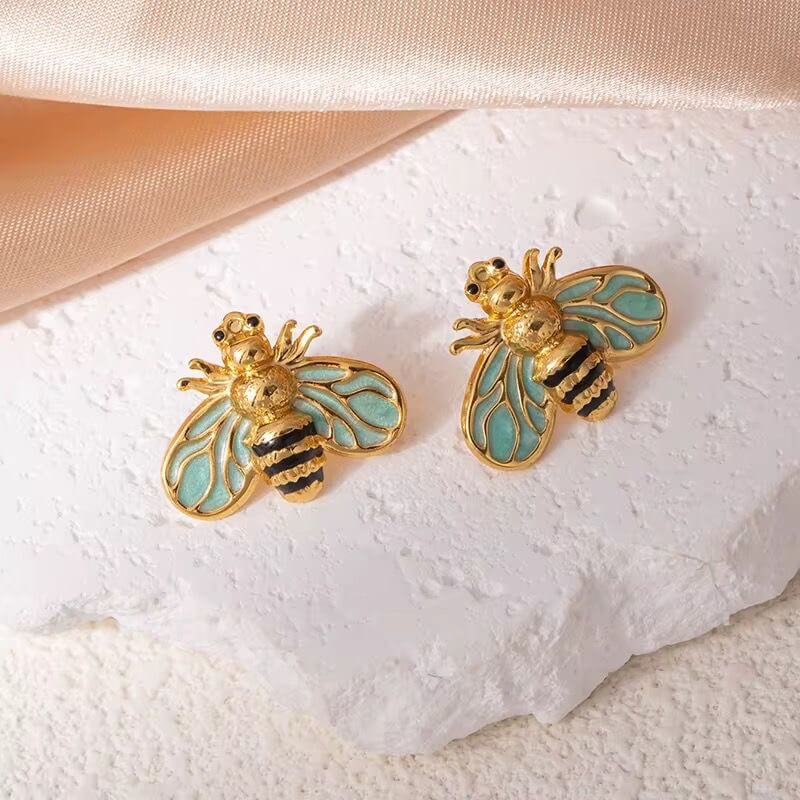 Bee stud earrings with gold-tone bodies, blue enamel wings, and small antenna details