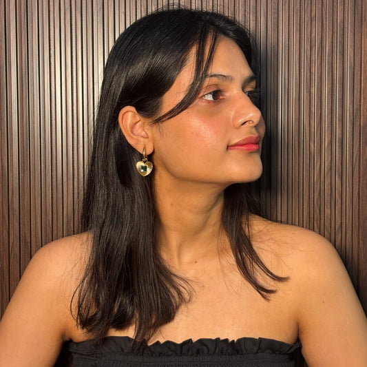Gold hoop earrings with heart pendant and green square gemstone on model