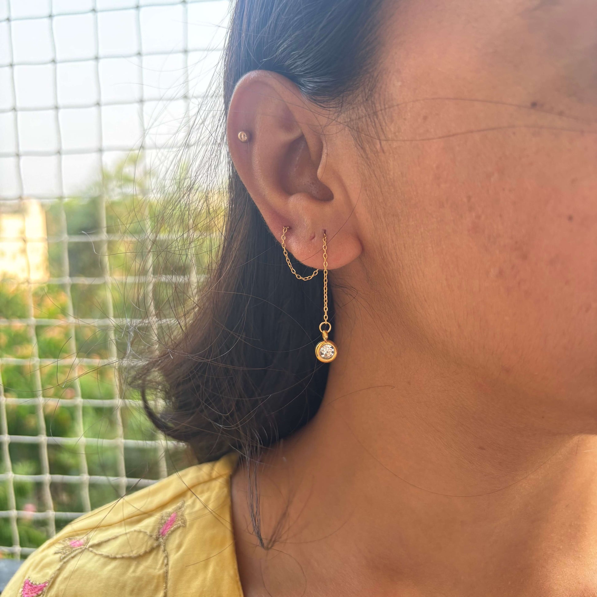 Gold threader drop earrings with round crystal charm on long chain, worn on ear