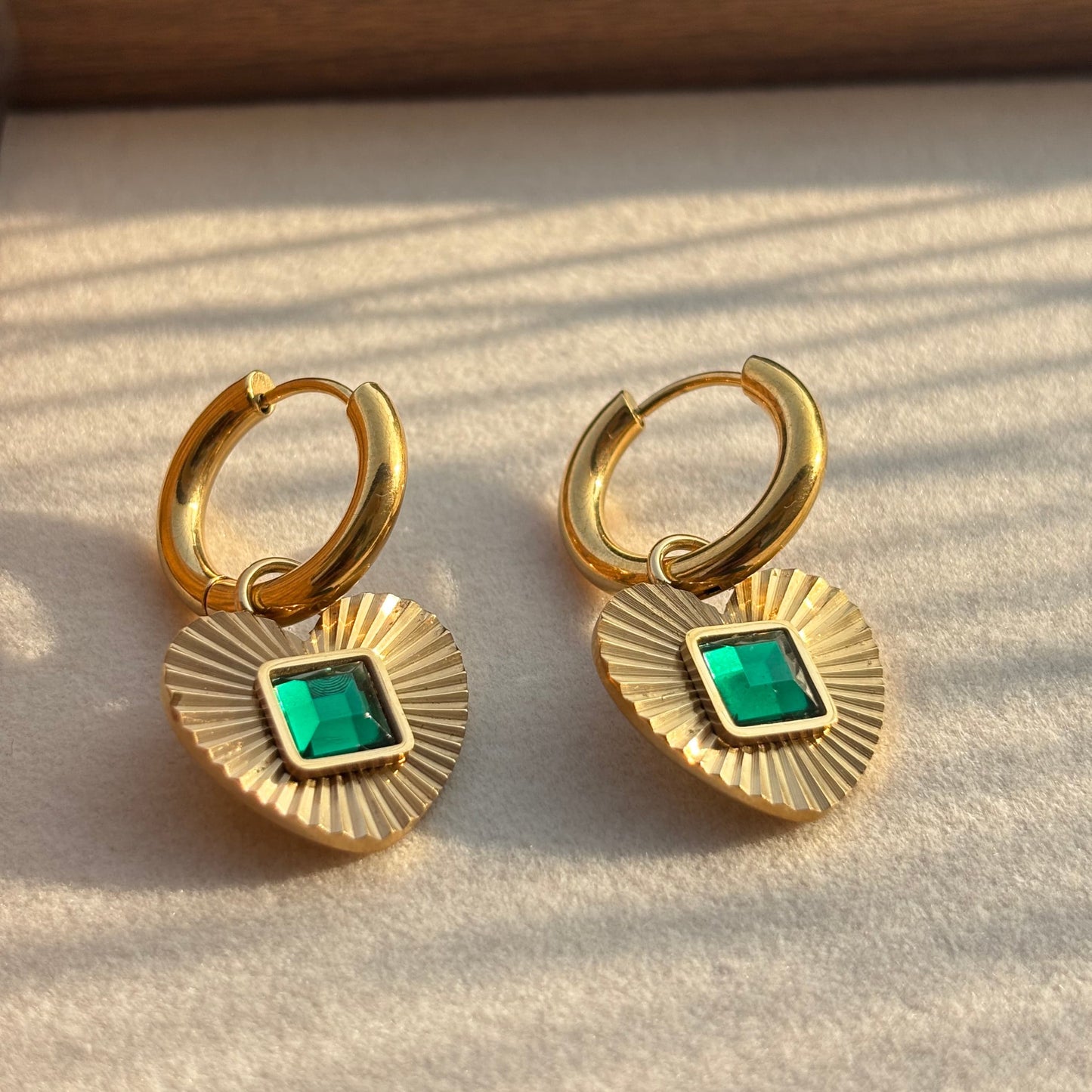 Gold hoop earrings with heart pendant and green square gemstone detail