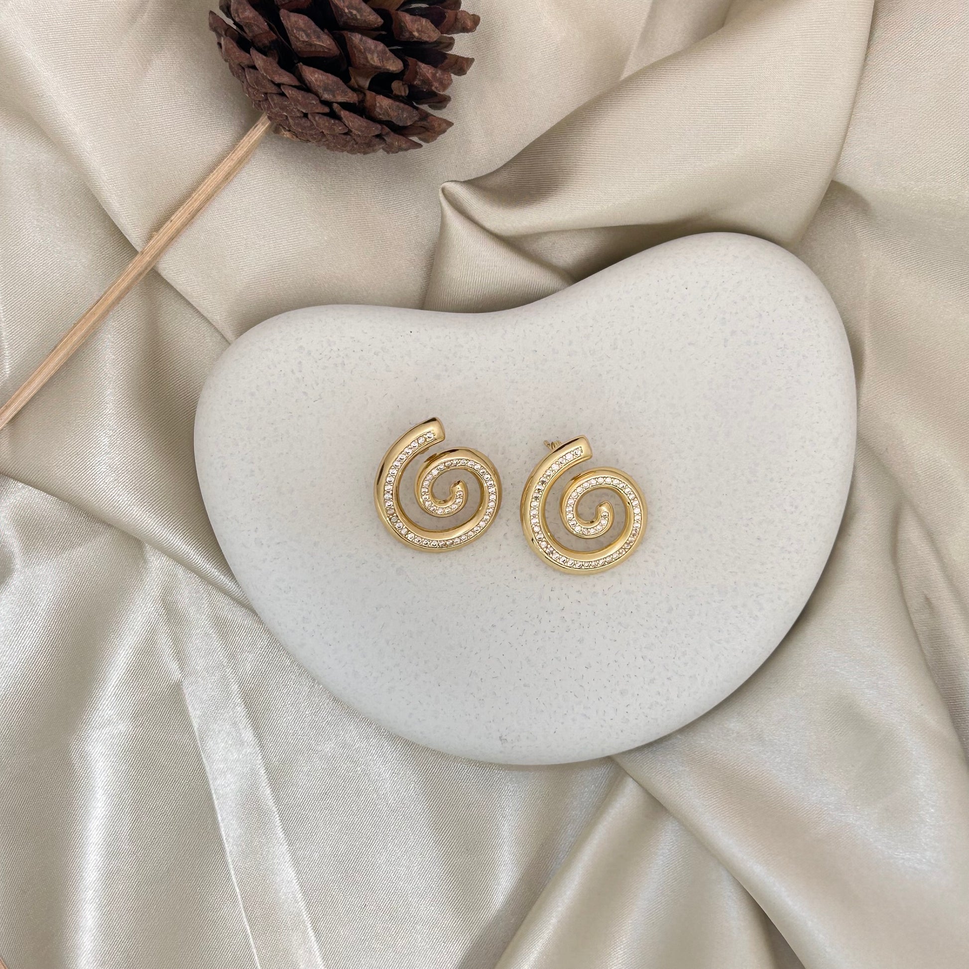 Gold spiral stud earrings with circular crystal pave swirl detail