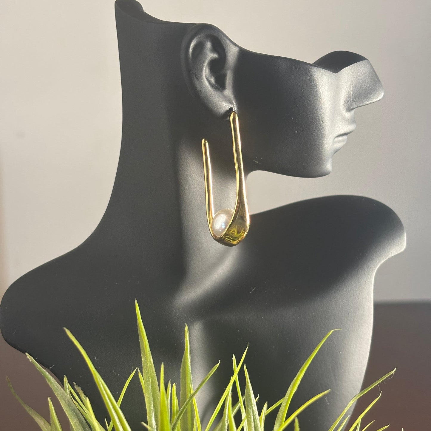 Gold-tone hoop earrings with white pearl detail in teardrop shape