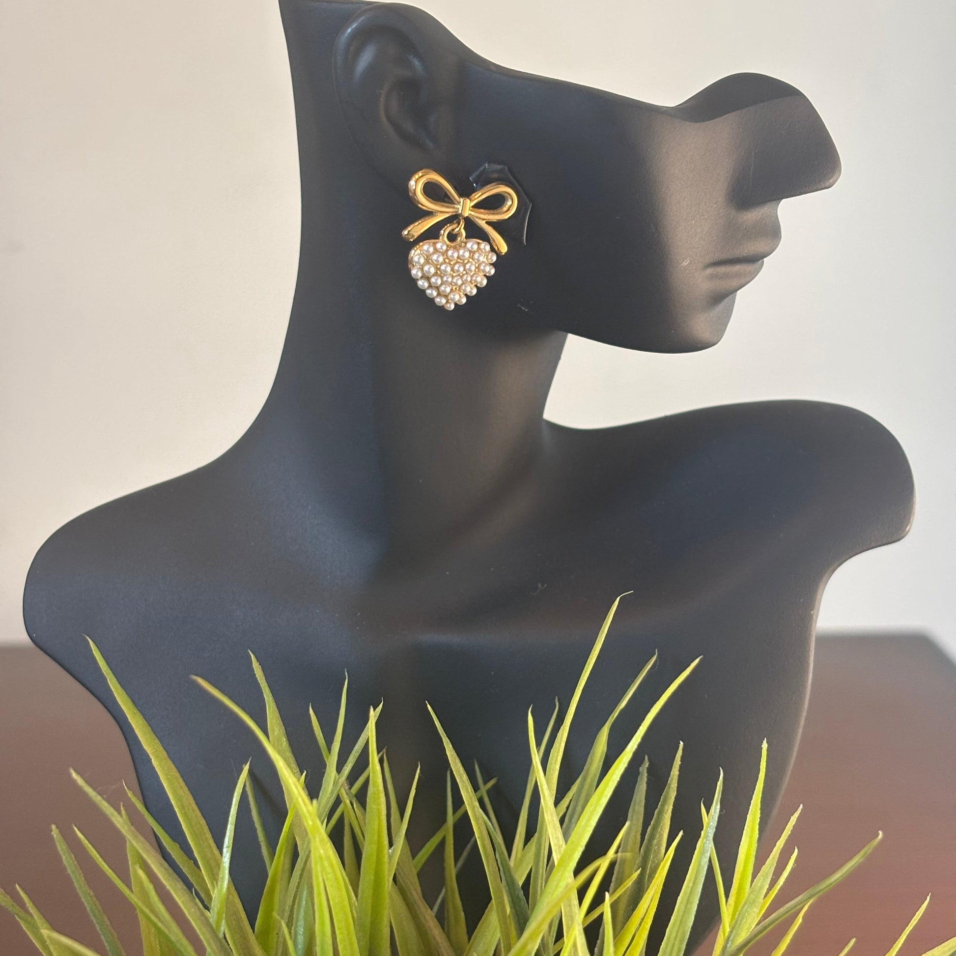 Pearl heart earrings with gold-tone bow detail on ear