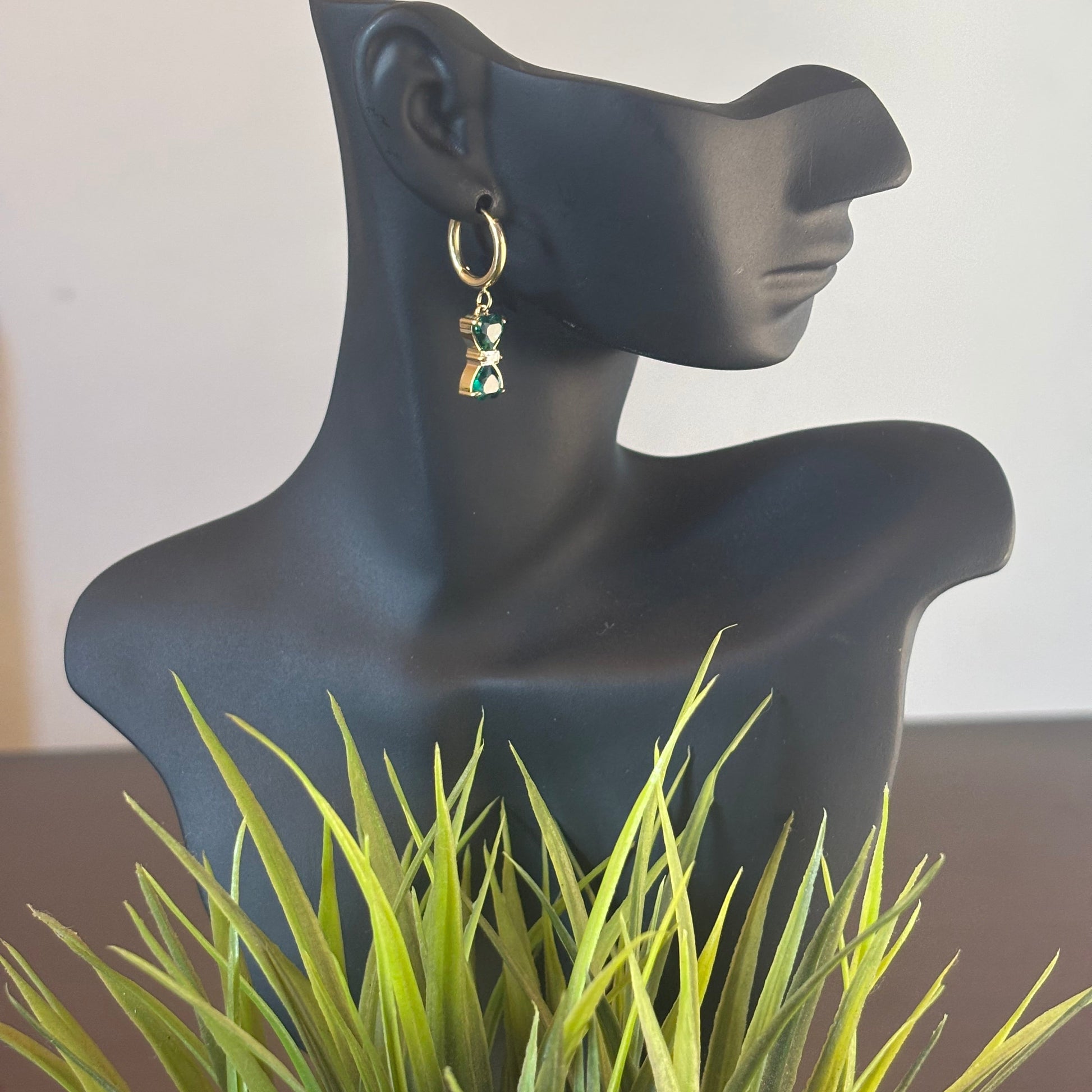 Gold hoop earrings with green bow-style drop charms, dangling