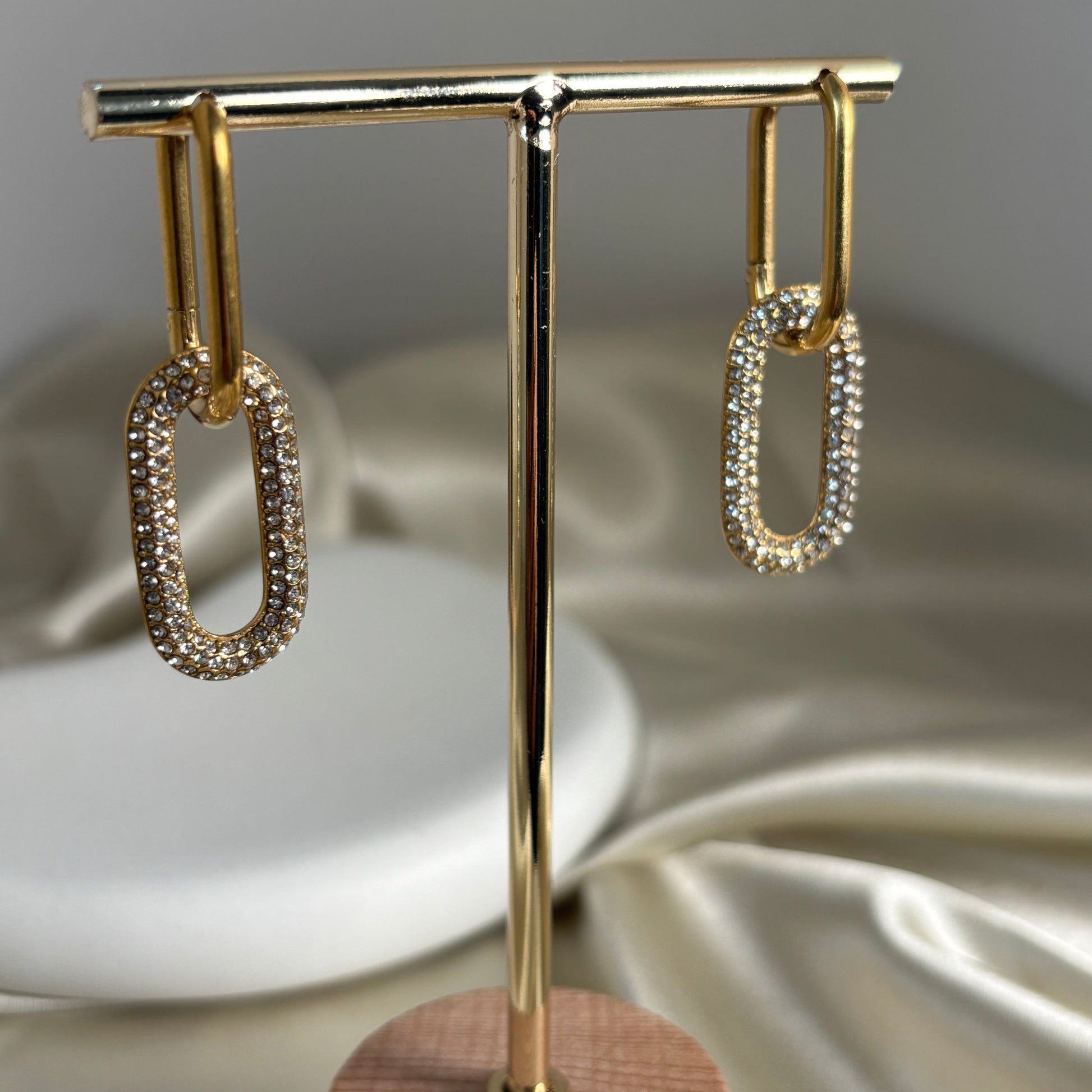 Gold-tone hoop earrings with oval cutout and rhinestone pave, open loop profile