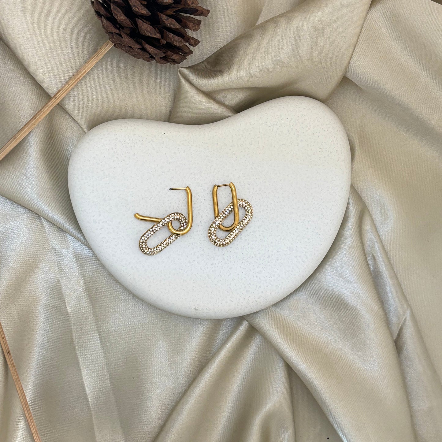 Gold-tone hoop earrings with linked oval shape and rhinestone pave, curved hook tops