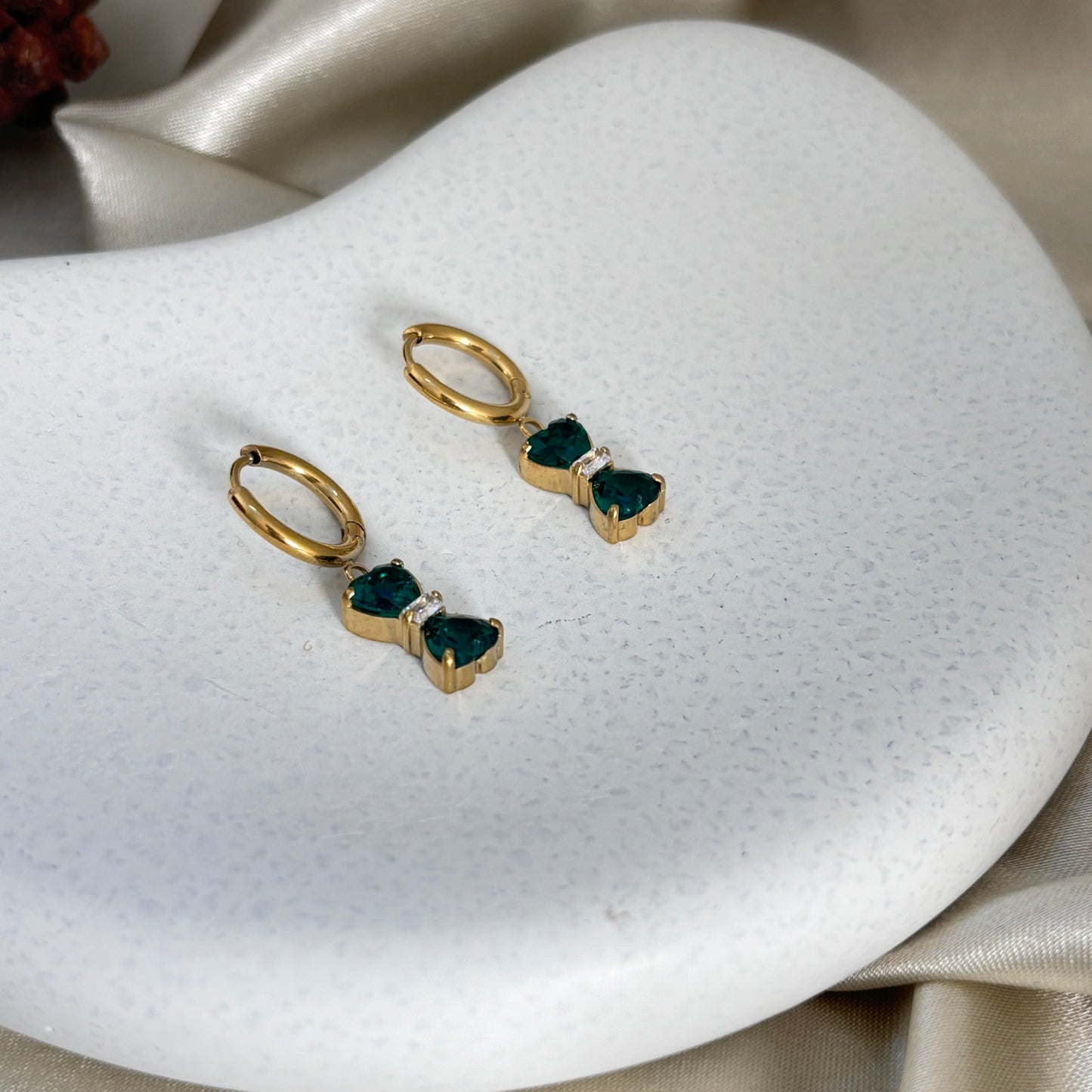 Pair of gold hoop earrings with emerald-green bow drop stones