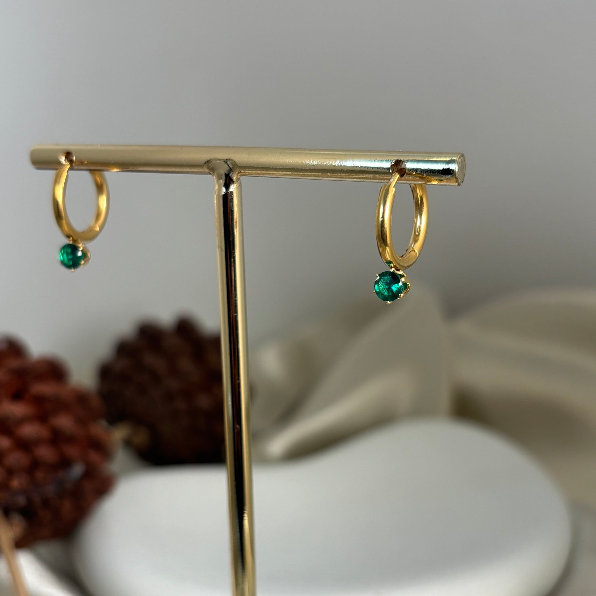 Gold hoop earrings with green drop charm on a vertical metal bar