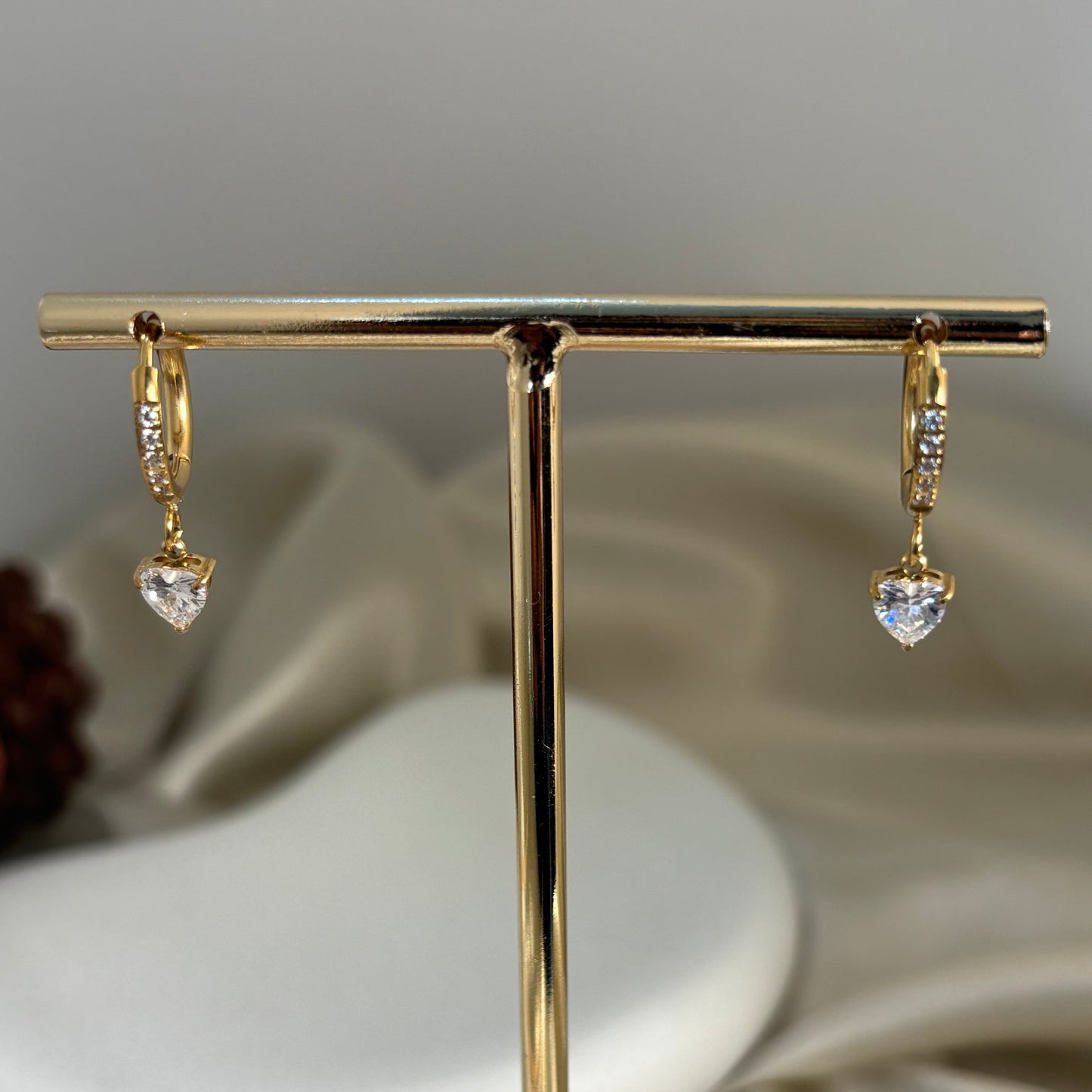Gold hoop earrings with small clear heart charm and rhinestone sparkle detail