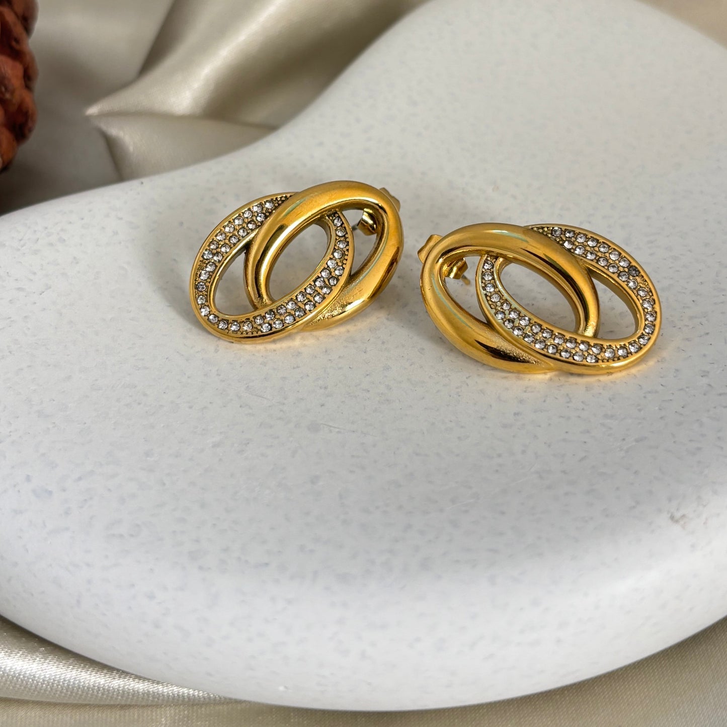 Gold-tone intertwined hoop earrings with rhinestone pavé edge