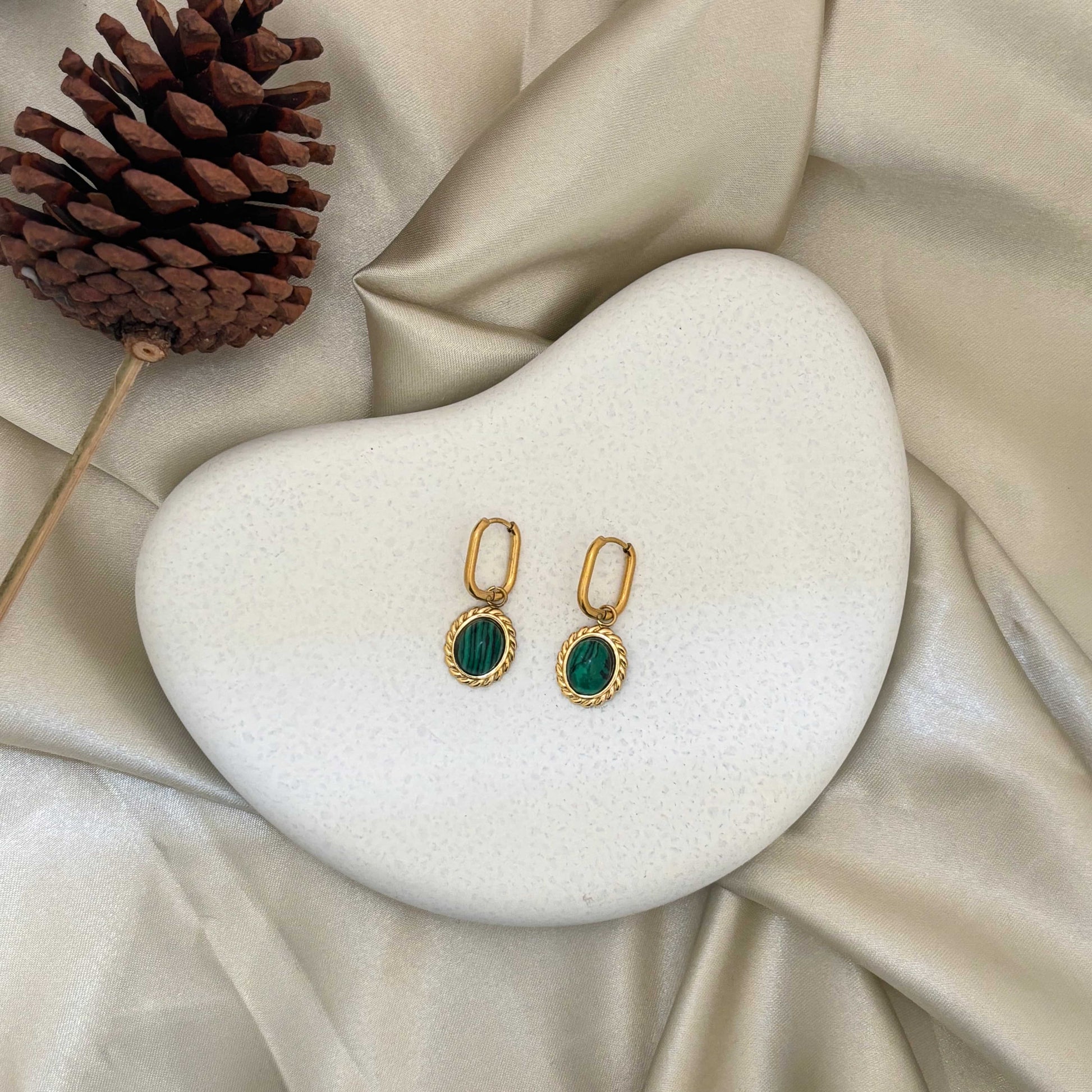 Pair of gold-tone drop earrings with green oval cabochon stones in decorative frames