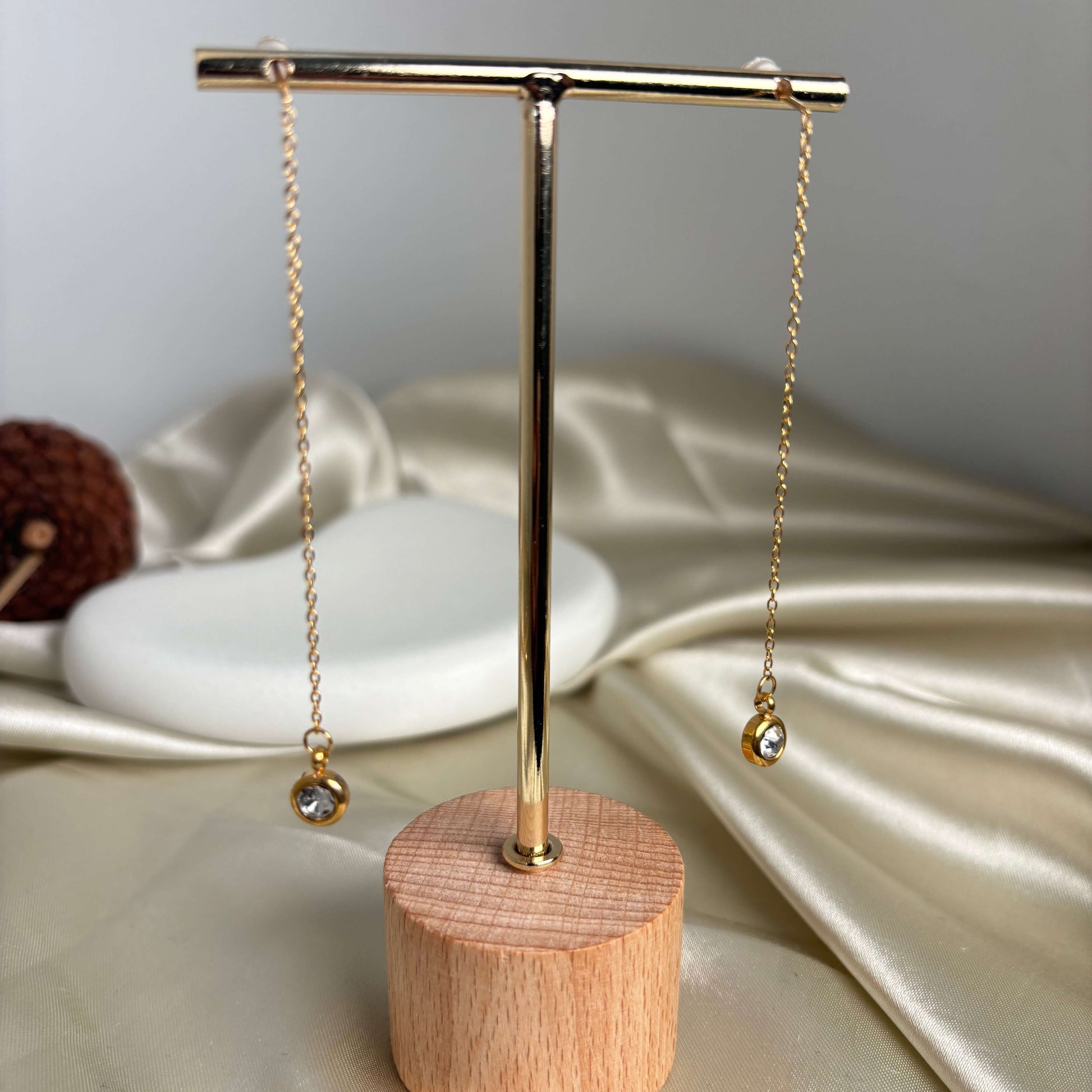 Gold threader drop earrings displayed on stand, two long chains with round crystal charms