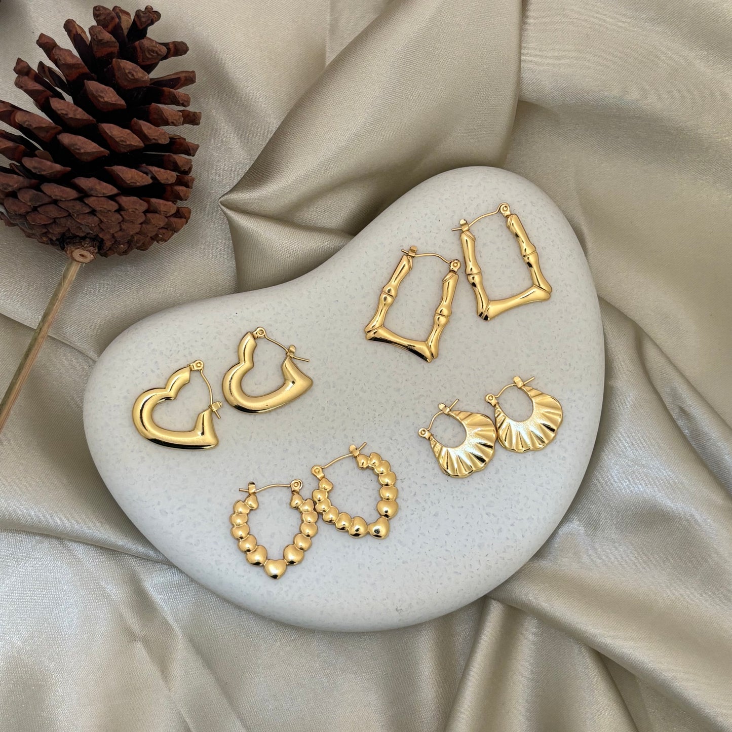 Gold hoop earrings set with fan and beaded hoop styles on display stand