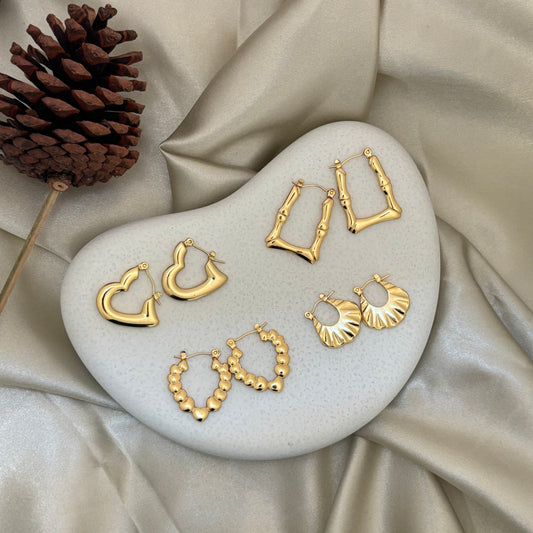 Gold hoop earrings set with fan and beaded hoop styles on display stand
