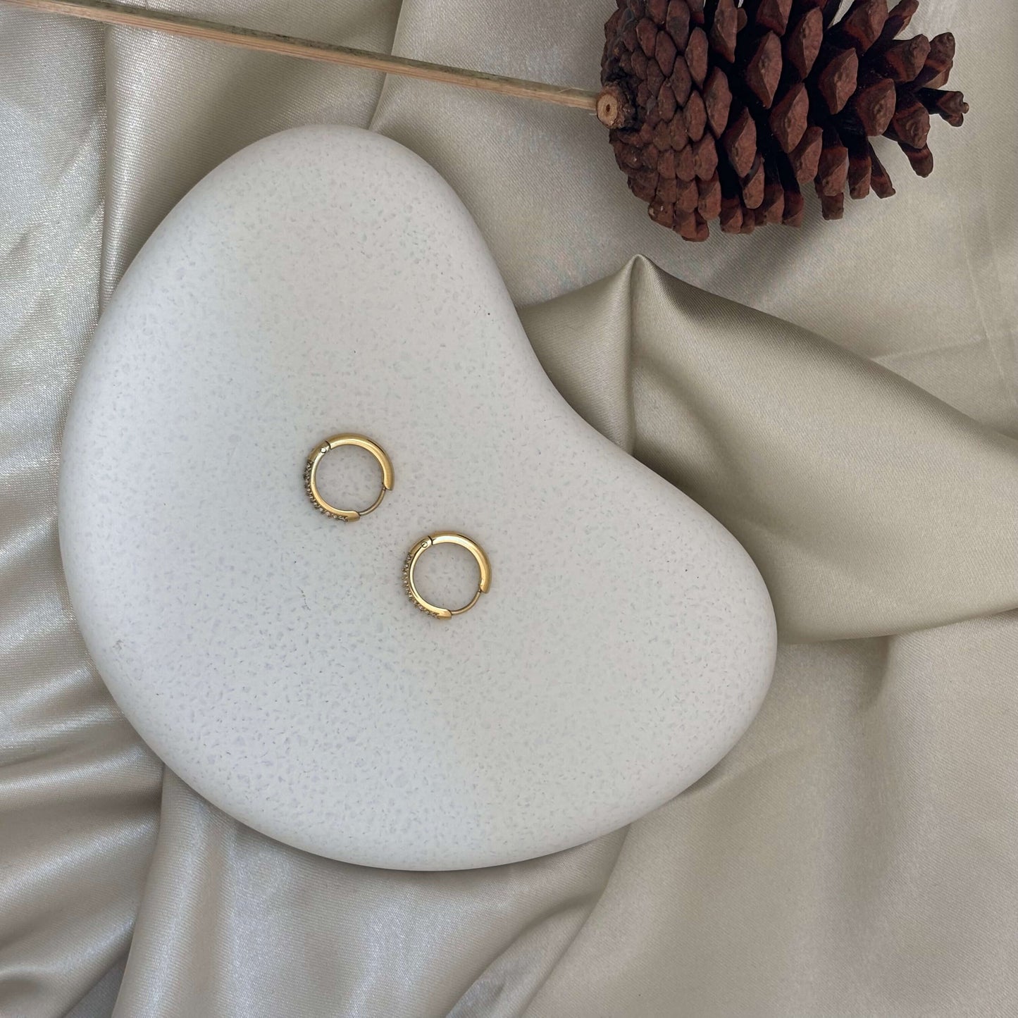 Gold huggie hoop earrings with crystal row, pair on white display