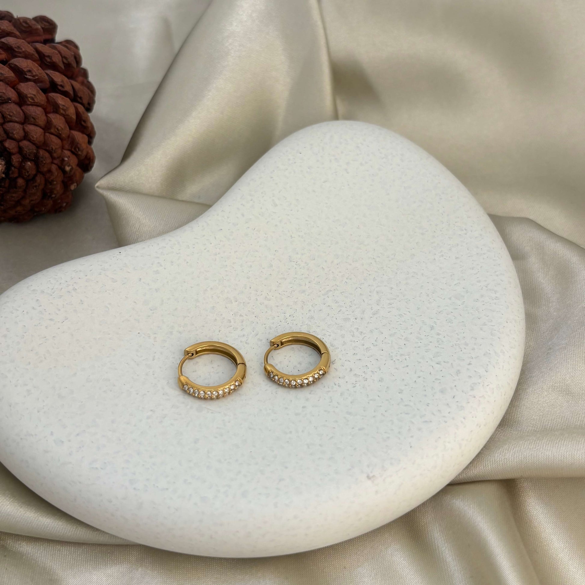 Gold huggie hoop earrings with crystal-studded front, shown as a pair