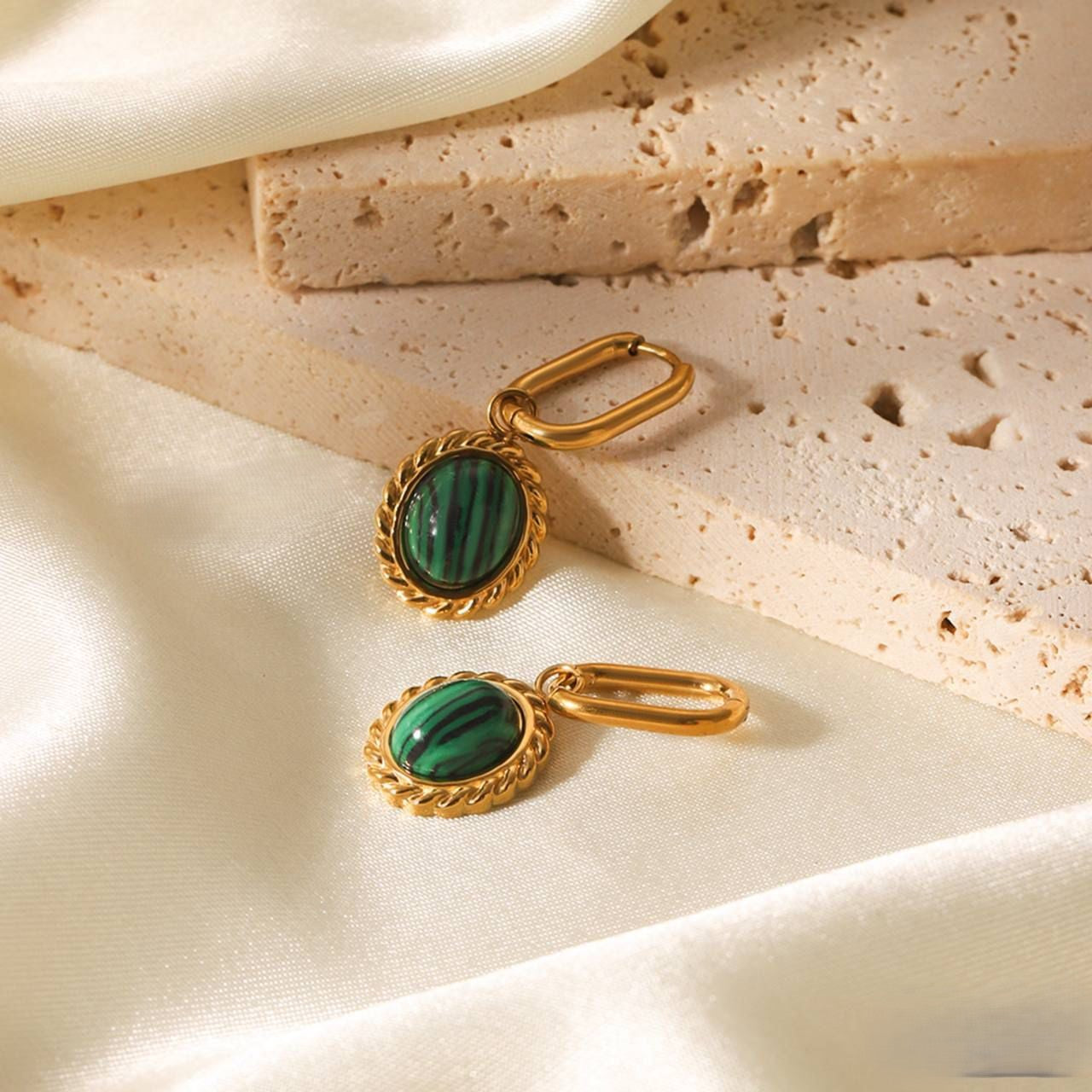 Gold-tone drop earrings with green oval stone and ornate bezel, on hinged hoops